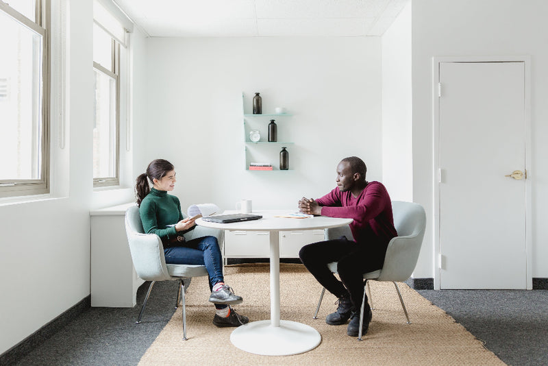 man and woman sat at white table talking HR Consultancy in Norfolk for Organisations Peak Performance HR